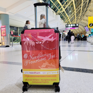 A suitcase with a red, orange, and yellow travel-themed cover that reads 